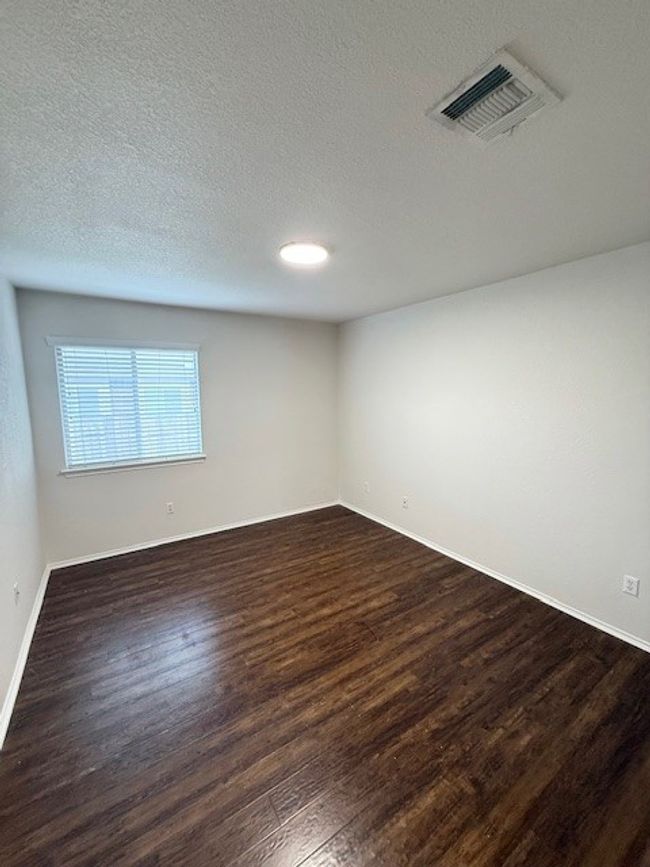 Empty room with dark wood-type flooring and a textured ceiling | Image 4