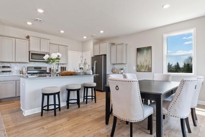 The kitchen island and dining area adjacent to the kitchen. Perfect for entertaining or having a family meal together. (Staged model in photographs, finishes may vary) | Image 2