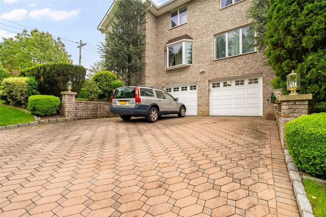 View of front facade with decorative driveway, a garage, and brick siding | Image 46