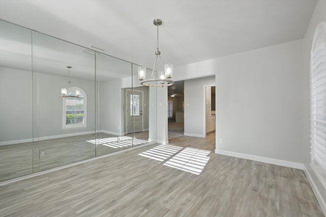 Unfurnished bedroom featuring baseboards, a notable chandelier, and light wood-style floors | Image 6