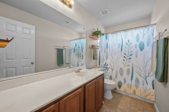 This full bathroom contains a long vanity for extra space, tile flooring, and a bathtub/shower combo. | Image 19