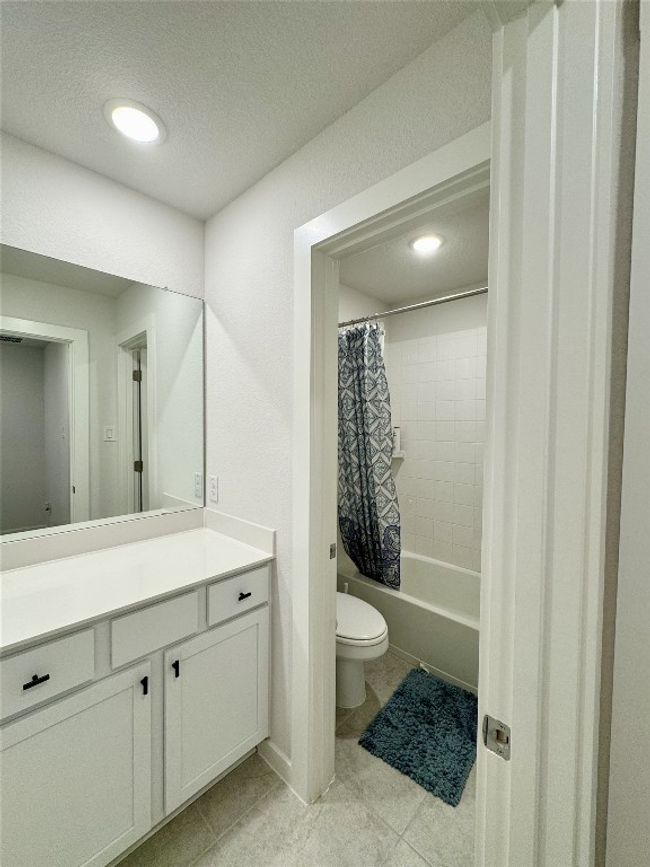 Bathroom with toilet, vanity, shower / tub combo with curtain, tile patterned flooring, and a textured ceiling | Image 10