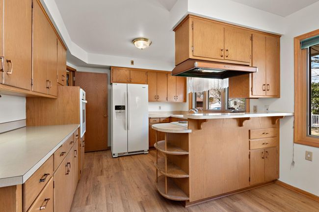 Nice kitchen with Jenn-Air cooktop for cooking and grilling, vent hood, wall oven, eat in kitchen/dining area and easy access to main floor laundry! | Image 19