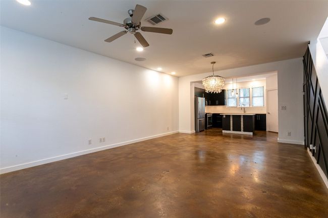 Unfurnished living room featuring a chandelier, concrete flooring, a ceiling fan, and recessed lighting | Image 6