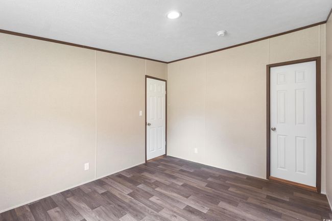 Unfurnished room with dark wood finished floors, crown molding, a smoke detector, and recessed lighting | Image 34