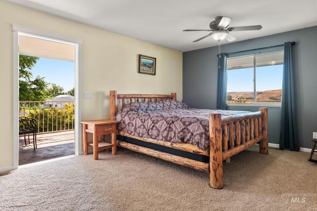 Carpeted bedroom featuring access to exterior covered patio & wrap around deck, multiple windows, and ceiling fan | Image 21