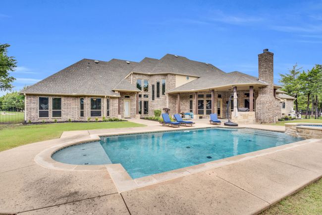 View of swimming pool featuring a patio area and a pool with connected hot tub | Image 37