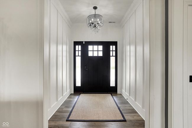 foyer entrance with visible vents, an inviting chandelier, dark wood-style floors, and a decorative wall | Image 6