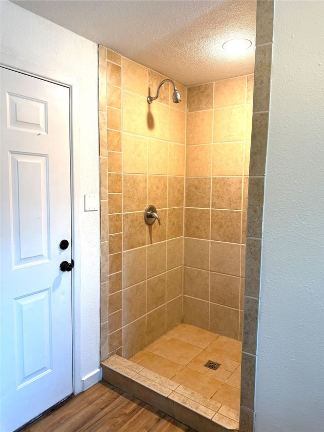Bathroom with a shower stall, a textured ceiling, a textured wall, and wood finished floors | Image 18