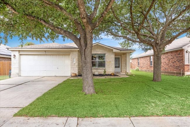 View of front of home featuring large trees, 2-car garage, front yard, and limestone siding | Image 27