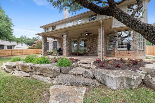Charming covered patio with stone landscaping and cozy seating areas, ideal for enjoying the peaceful, shaded backyard. | Image 30