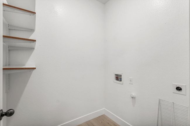 Washroom with electric dryer hookup, hookup for a washing machine, light wood-type flooring, and a textured wall | Image 12