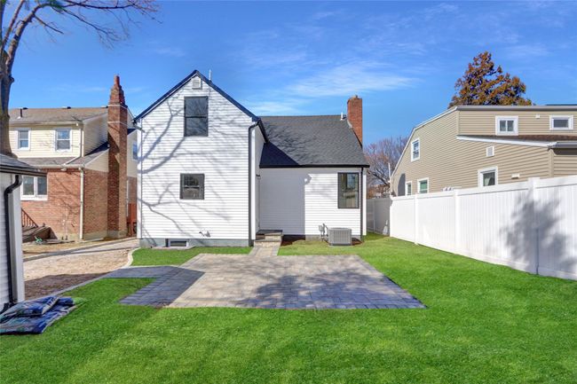 Rear view of house featuring fence private yard, central air condition unit, roof with shingles, a lawn, and a patio area | Image 27