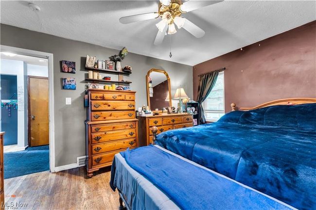 Bedroom featuring wood finished floors, baseboards, a textured ceiling, and a ceiling fan | Image 23