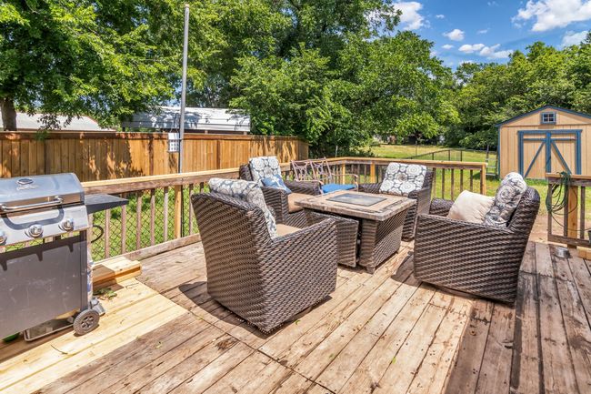 Wooden deck featuring a shed, a fenced backyard, a grill, and an outdoor living space with a fire pit | Image 24