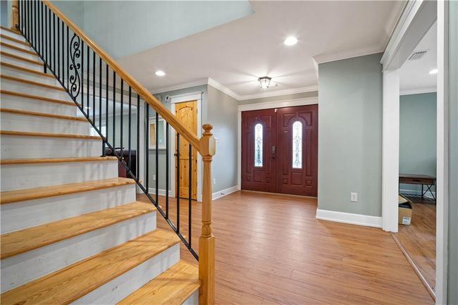 Entrance foyer with visible vents, light wood finished floors, baseboards, stairs, and ornamental molding | Image 14