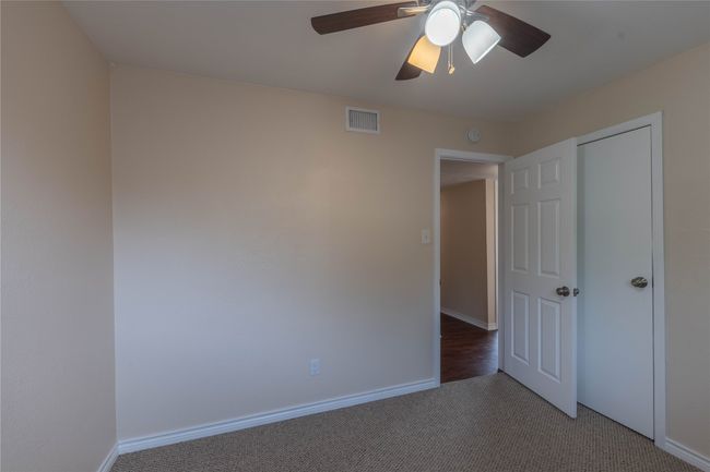 Unfurnished bedroom featuring light colored carpet, baseboards, and a ceiling fan | Image 23