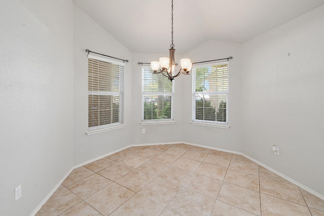 Empty room featuring vaulted ceiling, a chandelier, and light tile patterned floors | Image 9