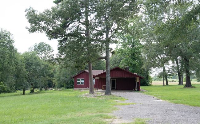 View of front of home with a chimney, gravel driveway, a front yard, and board and batten siding | Image 37