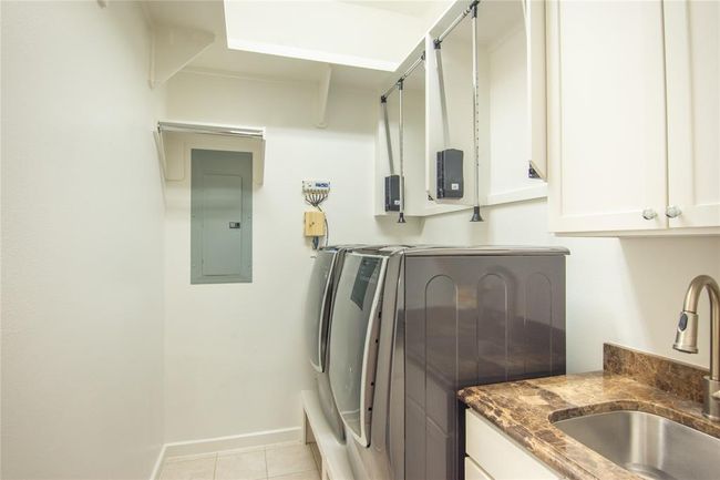 The utility room has hanging rods that you can pull down if needed. Cabinets for storage and a sink! | Image 29