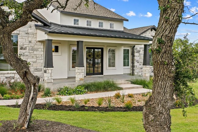 Entrance to property featuring a standing seam roof, stone siding, covered porch, and french doors | Image 36