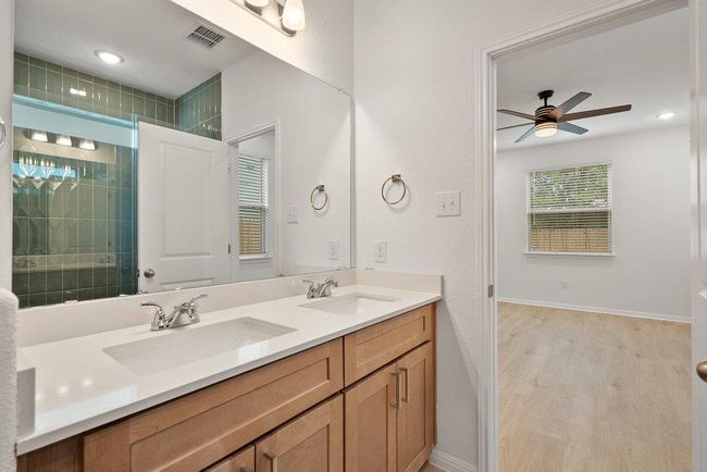 Bathroom featuring double vanity, a ceiling fan, wood finished floors, and a tile shower | Image 20