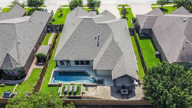 This aerial view showcases the spacious home with a well-maintained lawn, a private fenced backyard, and a beautiful in-ground pool. The property includes outdoor kitchen, perfect for outdoor entertaining. Located in a serene neighborhood, it offers privacy and ample outdoor space. | Image 33