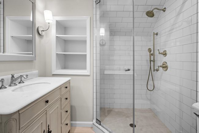 The accompanying en suite bath is beautifully updated with a glass-enclosed walk-in shower, polished subway tile, and an elegant vanity offering both style and storage. | Image 32