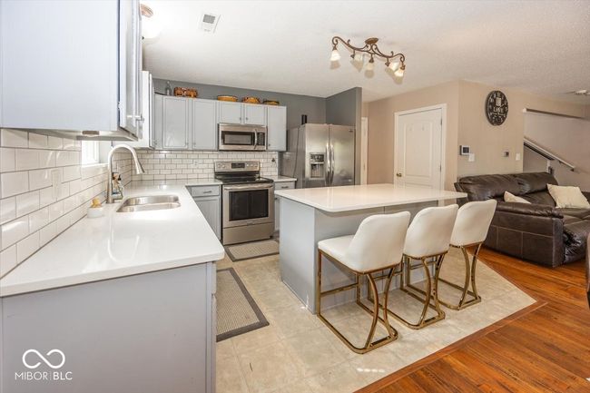 kitchen featuring a center island, a sink, a breakfast bar, appliances with stainless steel finishes, and visible vents | Image 9