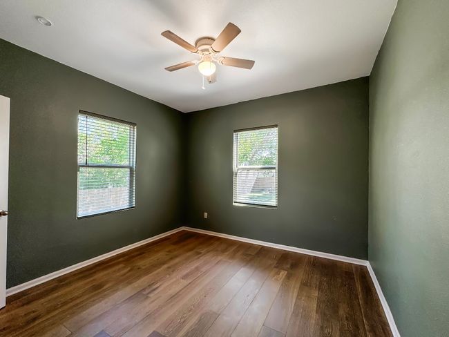 Spare room featuring plenty of natural light, wood finished floors, baseboards, and ceiling fan | Image 9