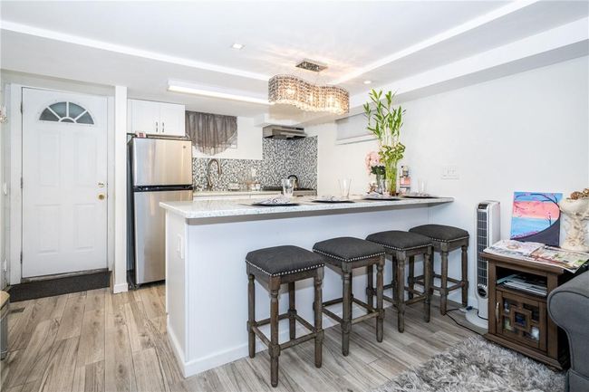 lower level kitchen with a breakfast bar area, stainless steel fridge, light wood-type flooring, and white cabinetry | Image 19