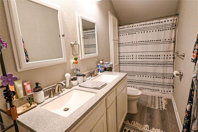Bathroom featuring double vanity, wood finished floors, toilet, and a textured wall | Image 28