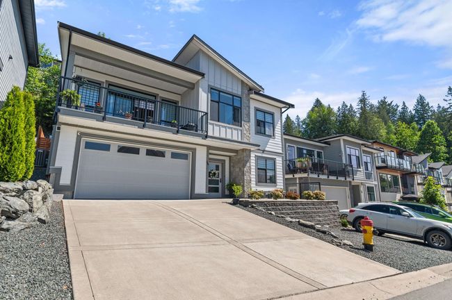 View of front facade featuring a balcony, driveway, a garage, and board and batten siding | Image 40