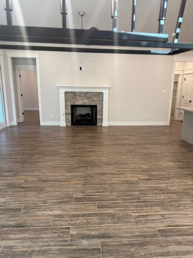 Unfurnished living room with a fireplace and dark wood-type flooring | Image 13