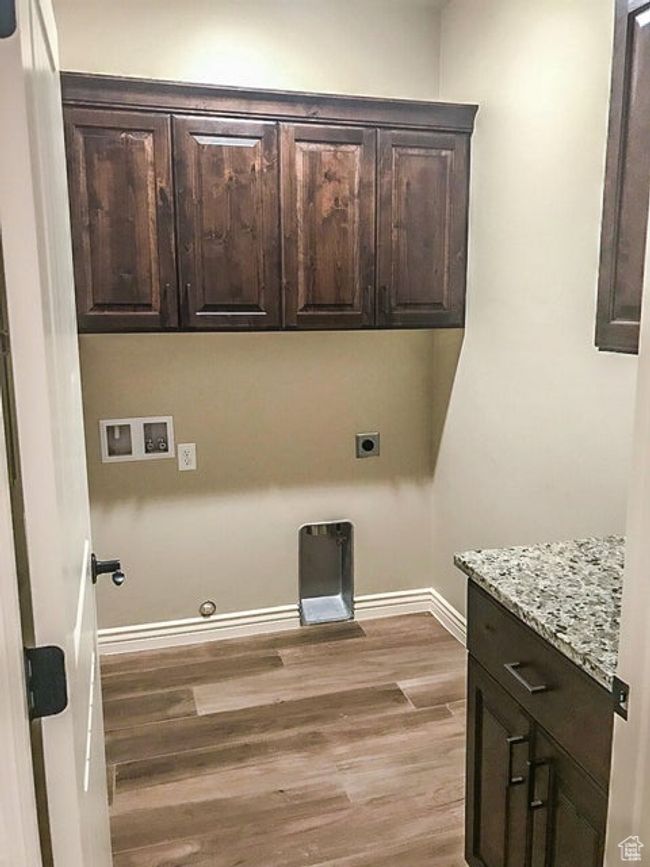 Laundry area with cabinet space, light wood finished floors, baseboards, gas dryer hookup, and washer hookup | Image 25