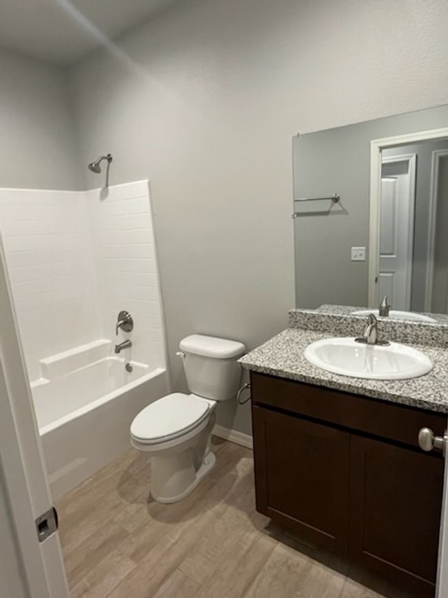 Bathroom with wood finished floors, toilet, vanity, shower / washtub combination, and baseboards | Image 27