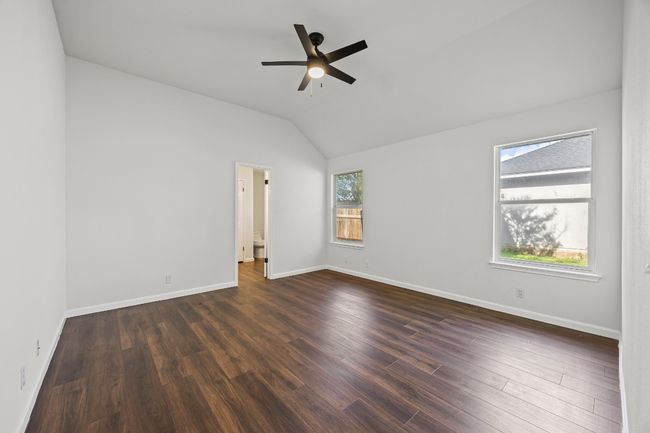 Empty room with a ceiling fan, dark wood finished floors, and vaulted ceiling | Image 16