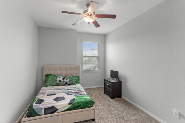 Wonderfully appointed secondary bedroom, featuring neutral paint, plush carpet, a window with privacy blinds, and a ceiling fan. | Image 15
