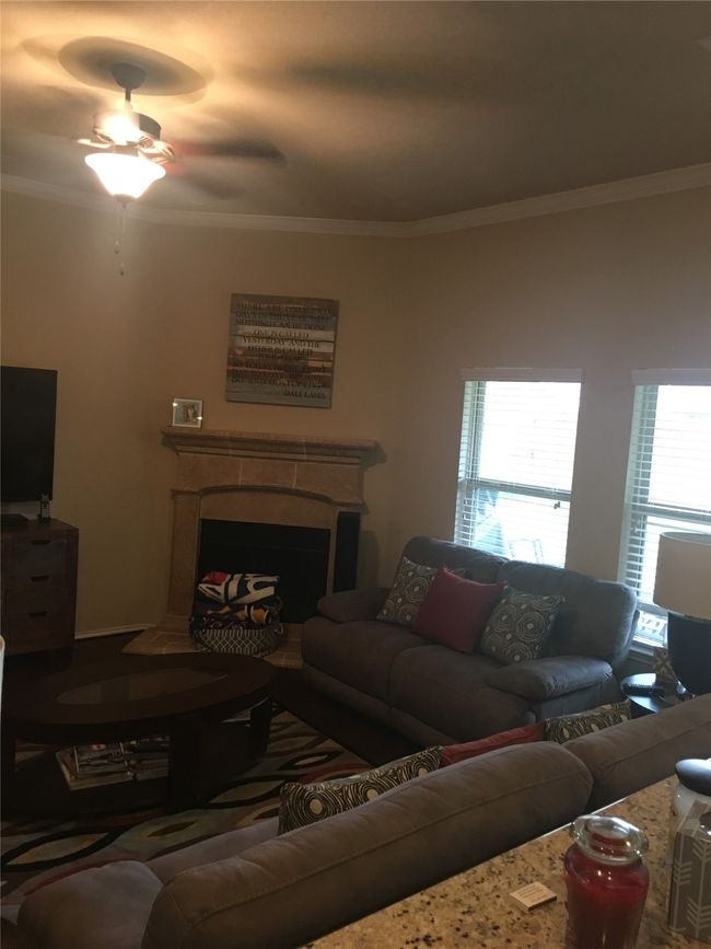 Living area with crown molding, a fireplace, and a ceiling fan | Image 7