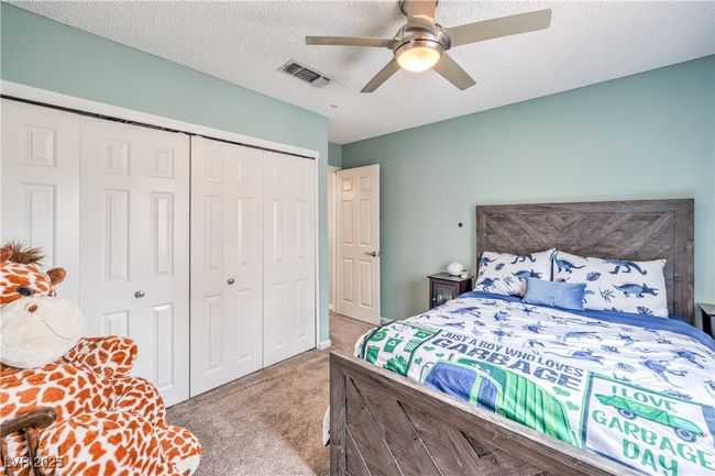 Carpeted bedroom with a ceiling fan, visible vents, a closet, and a textured ceiling | Image 35