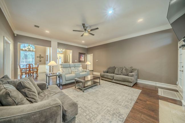 Living area with a chandelier, a ceiling fan, wood finished floors, ornamental molding, and recessed lighting | Image 27