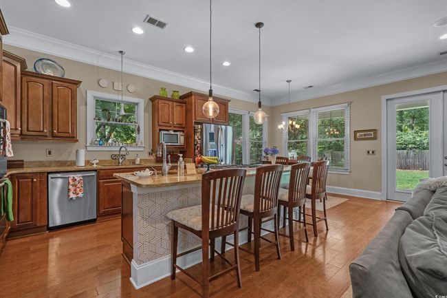 Kitchen with appliances with stainless steel finishes, open floor plan, a center island with sink, light wood-type flooring, and ornamental molding | Image 14