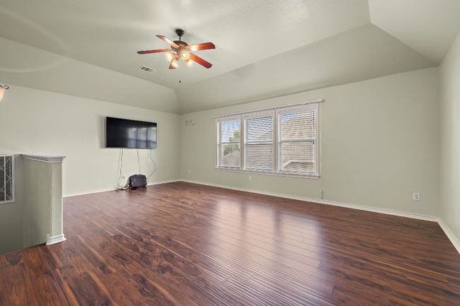 Spacious Loft room featuring vaulted ceiling, a ceiling fan, wood finished floors, and windows | Image 24