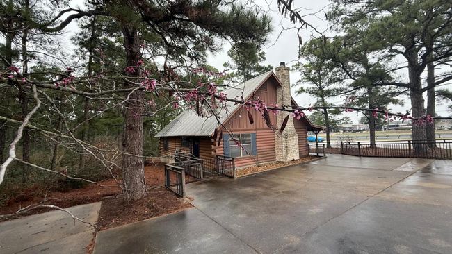 View of home's exterior featuring log exterior, driveway, metal roof, and a chimney | Image 4