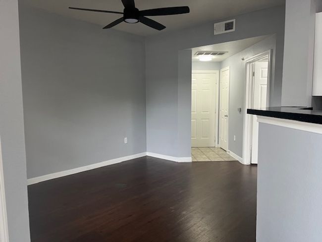 Empty room with wood finished floors, visible vents, baseboards, and ceiling fan | Image 7