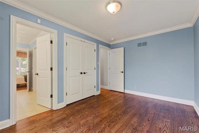 Unfurnished bedroom featuring crown molding, wood finished floors, and a closet | Image 27