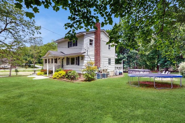View of property exterior with a trampoline, a chimney, a yard, and central AC. | Image 33