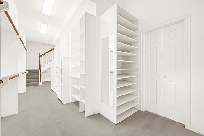 Luxurious primary closet featuring elegant custom built-in shelves and drawers for optimal storage. | Image 28