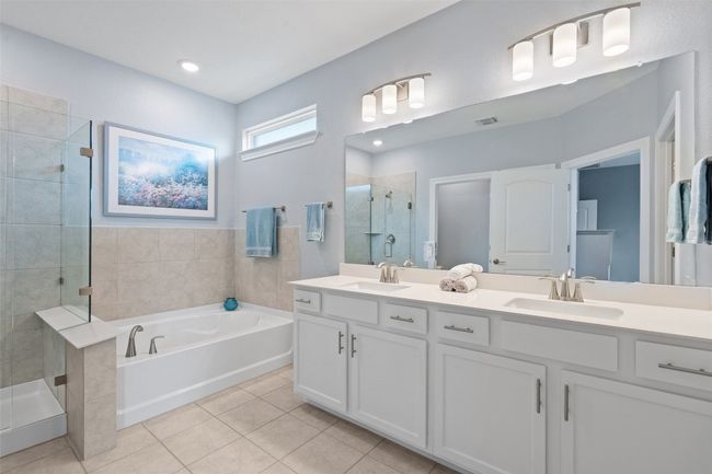The ensuite bathroom with dual vanities, garden tub, walk-in frameless glass shower, and an expansive walk-in closet. | Image 21
