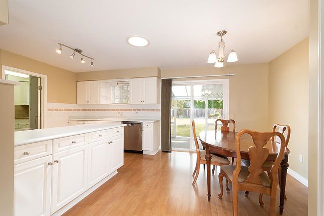Kitchen featuring dishwasher, a chandelier, light countertops, white cabinetry, and backsplash | Image 9